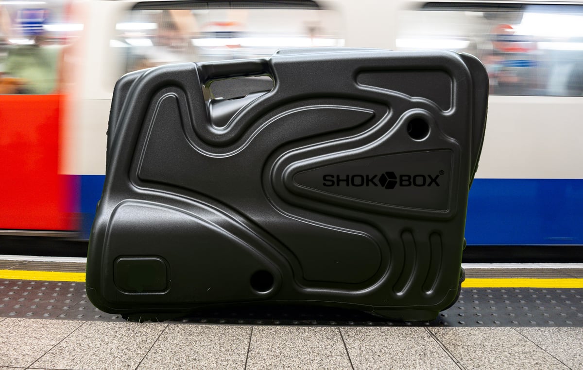 Black Shokbox bike travel case beside a moving train