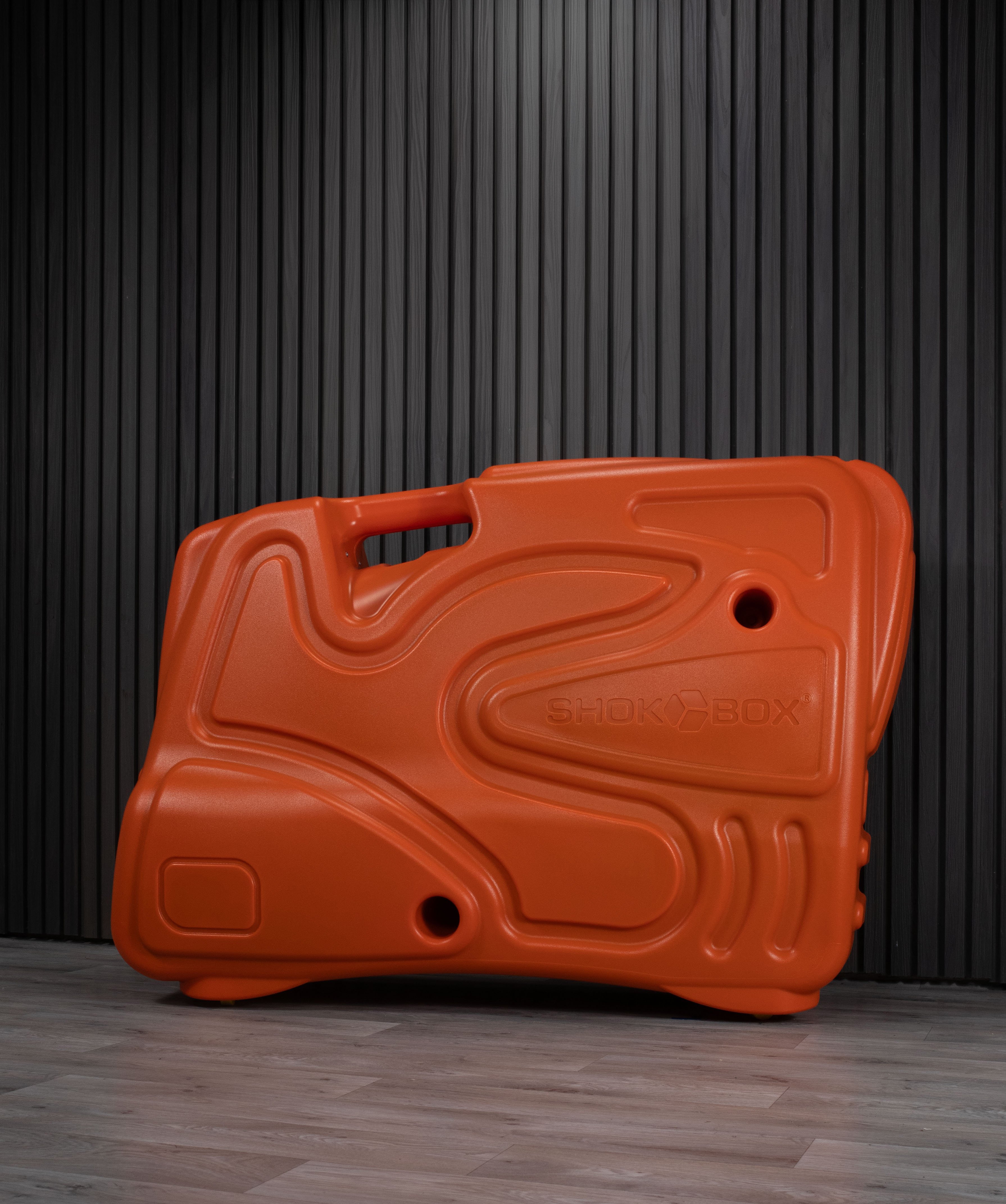 Orange Shokbox bike travel case against a dark wall